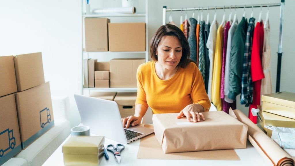 Mujer empresaria sonriente planificando su estrategia para septiembre con agenda y portátil en una oficina luminosa