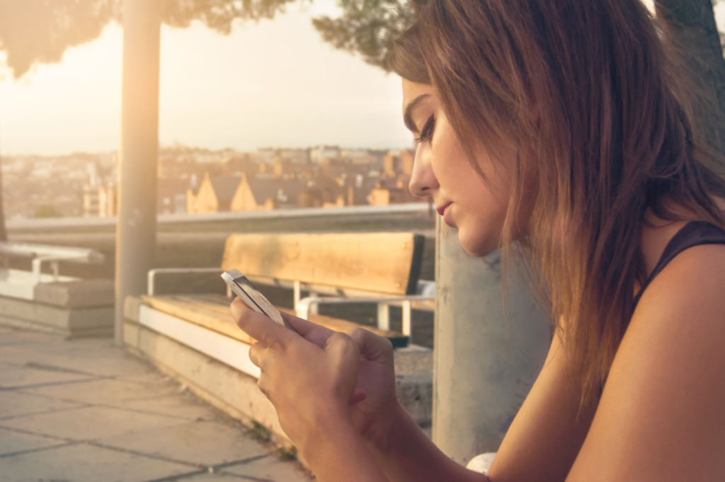 Chica joven leyendo reseñas de Google Business Profile en su móvil mientras decide qué negocio elegir
